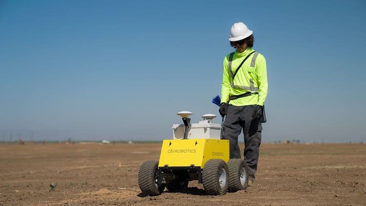 Construction worker operates CivDot construction layout robot for GPS layout on a flat terrain site