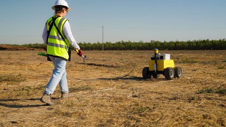 Construction worker using CivDot GPS land surveying equipment for layout on solar energy site.