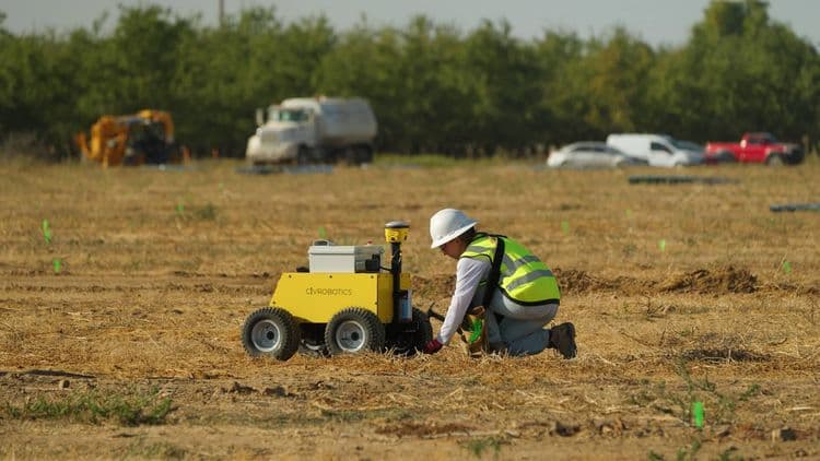 Construction worker using CivDot GPS land surveying equipment for layout on solar energy site.